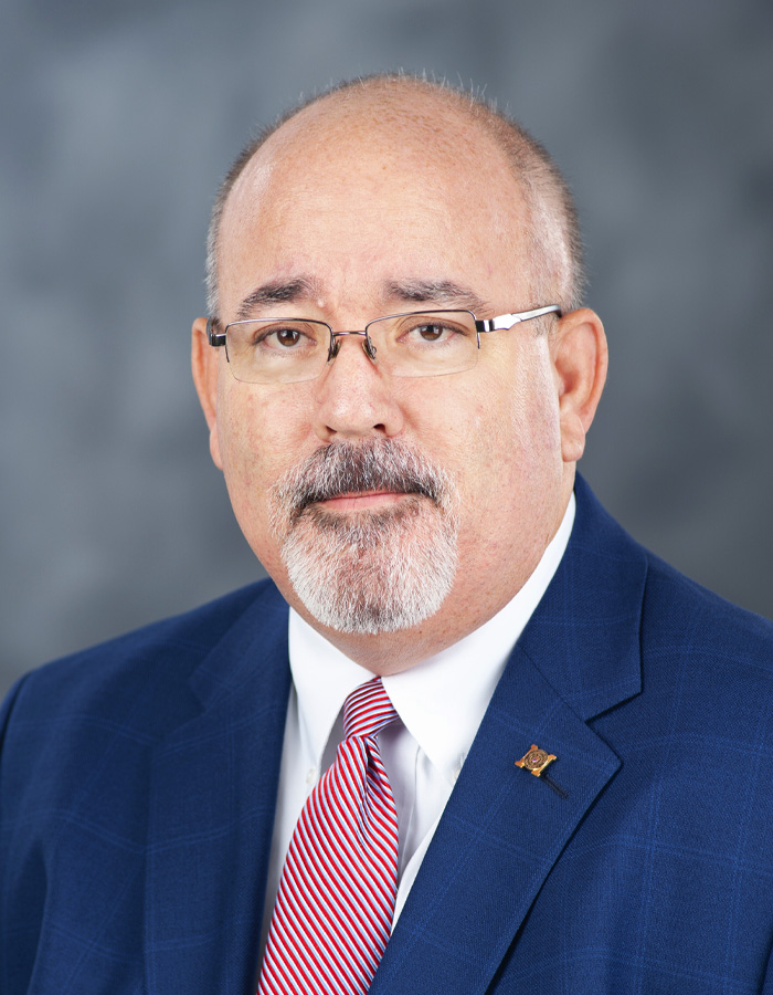 Portrait of Sid Salter wearing a blue jacket and red stripped tie